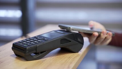 Pay by phone payment card reader Close-up woman hand using smartphone cashless wallet NFC technology to pay order on bank terminal Wireless Contactless payment in the store Close up - Powered by Adobe