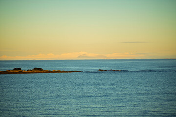Calm Sea with Distant Snowy Mountains at Sunset