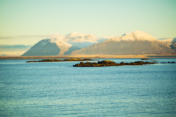 Snowy Mountains and Rocky Coastline in Soft Morning Light