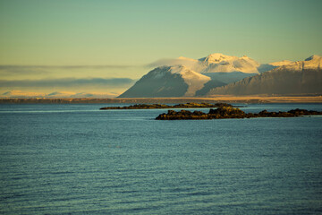 Snow-Covered Mountains and Rocky Coastline at Sunset