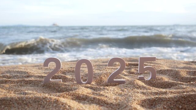 hand picks out the number 5, changing from year 2025 to 2026 for new year sign on summer beach at sunset, with ripple sea wave and beautiful nature at background, 2026 New Year celebration concept