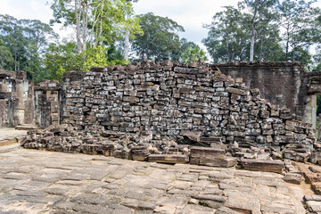 Weathered stone wall of collapsed temple structure in dense jungle. Calm, historical mood. Suitable for heritage, travel, architecture photography