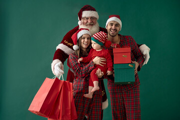 Fototapeta premium happy family with little child and santa claus with golden confetti on green background