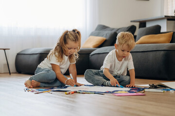 Markers and drawing board. Little kids are playing together in the domestic room at daytime
