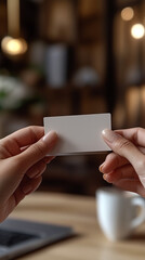 Hands gently present a blank white business card, offering ample copy space for custom text or logo branding.