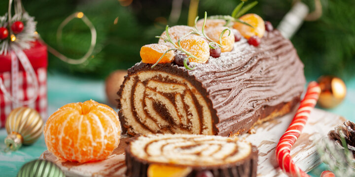 Yule log roll cake with chocolate ganache  on Christmas decorated background