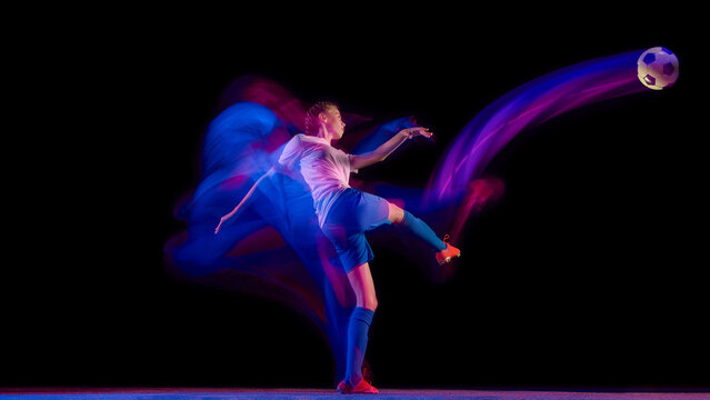 Female athlete kicking soccer ball with dynamic light trail. Concept of sport creativity, advertising visuals, motion energy, and athlete training design.