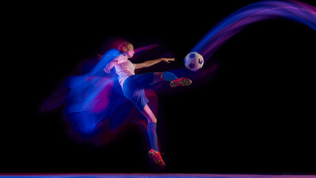 Woman football player performing mid-air kick in neon motion. Concept of sport action visuals, energy advertising, agility training, and brand campaigns.