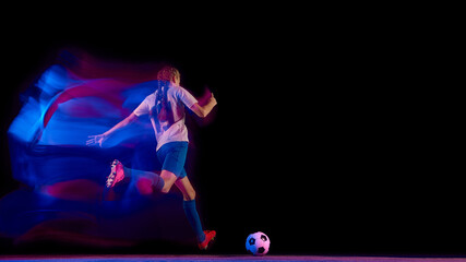 Female football player running to strike ball in green-blue motion trail. Concept of sport energy visuals, body in motion, advertising campaigns, and athletic training performance.