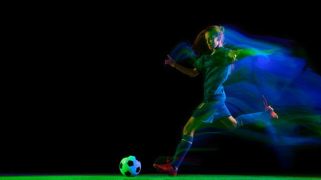 Female soccer player jumping to head ball in glowing blue motion light. Concept of coordination training, sport advertising, motion energy, and performance visuals. - Powered by Adobe