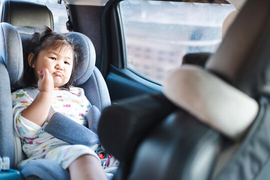 Cute little Asian girl sitting in a car seat suitable for children inside the car,Little girl sist in car and smile to camera,Transport, safety, childhood road trip and people concept - Happy little.