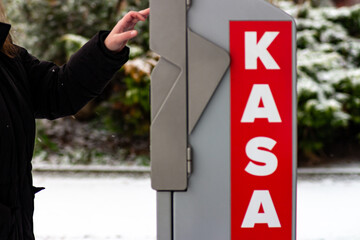 Close up of a person pointing at an outdoor payment kiosk with a red KASA sign