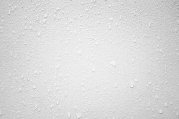 A white wall surface with visible water droplets creating a natural textured pattern.