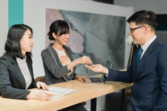 Professional woman transferring access key token to client executive, symbolizing real estate ownership, digital security, or project handover - Powered by Adobe
