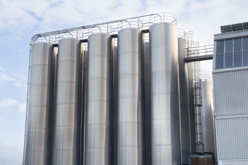 Large stainless-steel industrial silos at a modern production facility