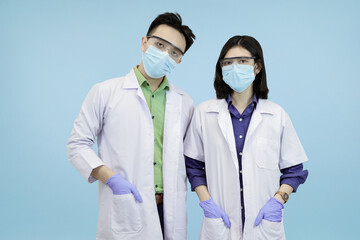 Confident Asian medical standing ready and looking directly at the camera, symbolizing health authority in blue studio background