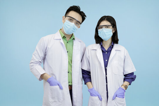 Confident Asian medical standing ready and looking directly at the camera, symbolizing health authority in blue studio background