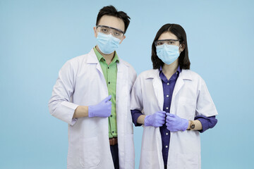 Confident Asian medical standing ready and looking directly at the camera, symbolizing health authority in blue studio background