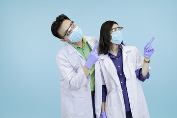 Asian medical pointing upwards, signifying instruction, attention, or a new successful direction in blue studio background