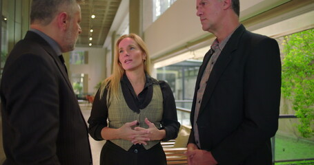 Confident female colleague presenting team members with handshake in office hallway, business professionals meeting during formal workplace introduction