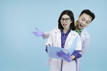 Astonished Asian science professionals reacting to a breakthrough, excitedly viewing data on a digital tablet during research in blue studio background