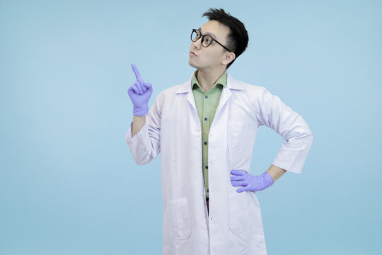Happy Asian female scientist or doctor in a lab coat and gloves, while presenting data or information on a digital tablet, set against a clear blue studio background