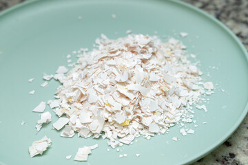 Crumbled eggshells on a teal plate, composting or soil enrichment by reusing kitchen scraps