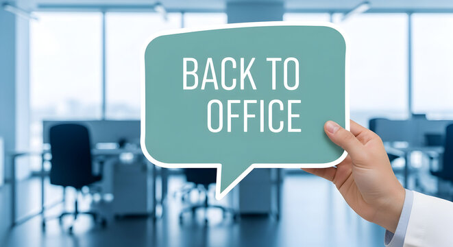 Hand holds a speech bubble with the text "Back to Office" in a modern office space signaling a return to inperson work and collaboration in a professional environment with desks and chairs visible