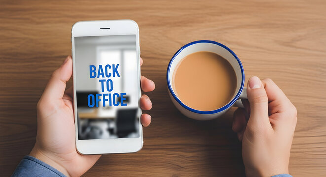 Person holding a smartphone displaying "Back to Office" message with a cup of coffee on a wooden desk symbolizing return to work and office life after remote work with focus on workplace transition