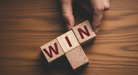 Hand places wooden blocks spelling "win" on a wood surface symbolizing success victory and achievement in business sports or personal goals conveying a message of triumph and motivation