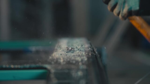 Hammer Smashing Glass Sheet with Flying Shards in Workshop