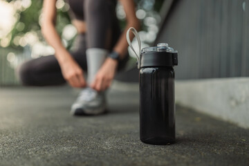 Reusable sports water bottle on ground during outdoor workout &ndash; healthy lifestyle, fitness hydration, running preparation, sustainable active living concept