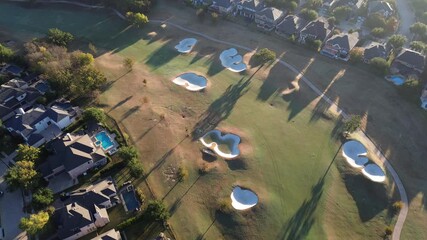 Distinct sand bunkers and paved paths weave through Lantana Golf Club fairway, flanked by mansion homes with pools. Autumn foliage and long shadows enhance the visual balance of land use, Texas