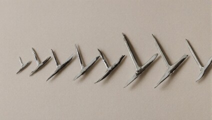 An array of metal, T-shaped objects are lined up on a neutral beige surface, varied in size