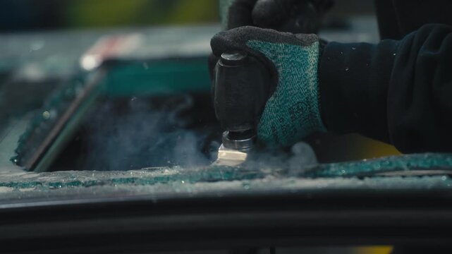Worker Using Pneumatic Scraper on Shattered Glass Pane with Smoke
