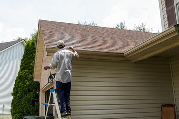 Fototapeta premium A portrait of a black man cleaning out gutters at a home 