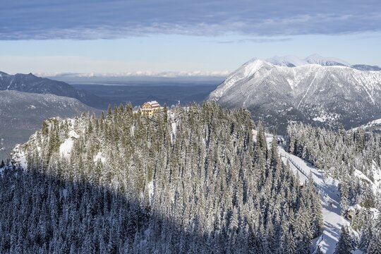 Snowy forest and Kreuzeckhaus mountain hut in the Garmisch Classic ski area in winter, at the back peaks of the Ester Mountains, Wetterstein Mountains, Garmisch-Partenkirchen, Bavaria, Germany