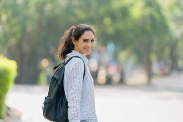 Smiling young woman turning back on a path, confident invitation, welcome, and the start of a new journey or commute