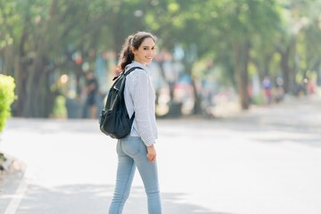 Smiling young professional woman turning back on a sunny path, confident invitation, welcome, and the start of a new journey