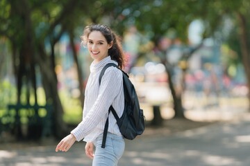 Smiling young professional woman turning back on a path, confident invitation, welcome, and the start of a new journey