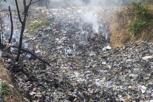 Coking rubbish dump, rubbish pit with waste and plastic rubbish, karst landscape near Vang Vieng, Vientiane province, Laos