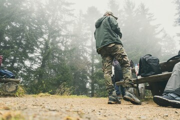 Fototapeta premium Hikers navigate the mist-shrouded paths of the Piatra Craiului Mountains in Romania. Dense trees frame the scene, creating an enchanting atmosphere for outdoor adventurers