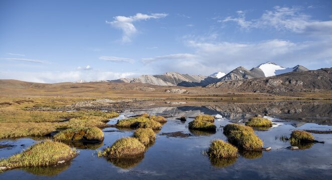 Mountain peaks reflected in a mountain lake, autumnal plateau with brown grass, glaciated and snow-covered peaks, Ak Shyrak Mountains, near the Kumtor gold mine, Tian Shan, Kyrgyzstan