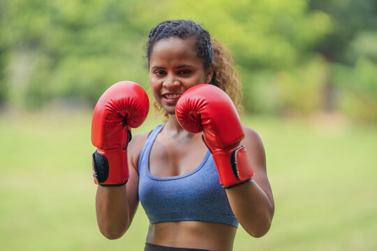 Smiling woman in boxing gloves, confidently ready for a challenge, female empowerment, business strategy, and fitness