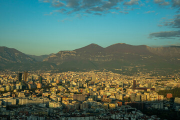 Fototapeta premium Tirane, Albania November 01 2025. Close-up of Tirana's dense, colorful core, featuring modern high-rises silhouetted against the dark, protective Dajti mountain backdrop.