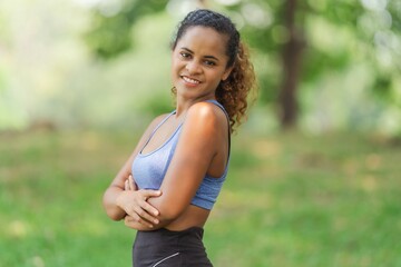 Confident woman smiling with arms crossed, self-assurance, inner strength, fitness achievement, and approachable wellness