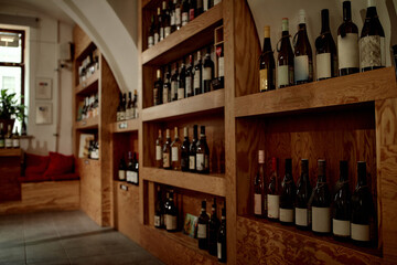 Empty wine tasting room with wooden shelves displaying assorted wine bottles, no people visible, interior setting suggesting preparation for wine tasting event or professional evaluation