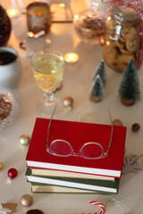 Cookie jar, tea, wine, nuts, books, lit candles and Christmas decorations on the table. Cozy Christmas hygge at home. Selective focus.