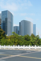 Urban road, greenery, and tall modern skyscrapers
