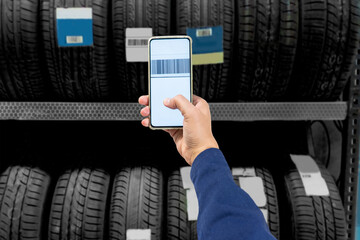 Employee scanning a bar code on a tire at a garage shop using a cell phone.